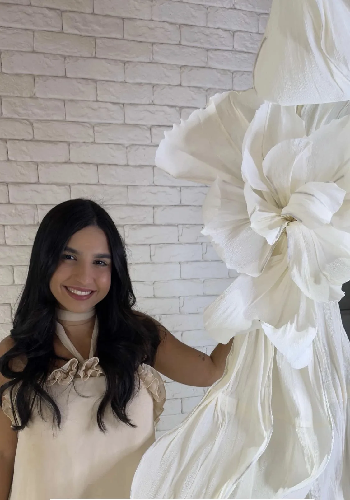 Aluna ao lado de Flor Oversized branca no ateliê